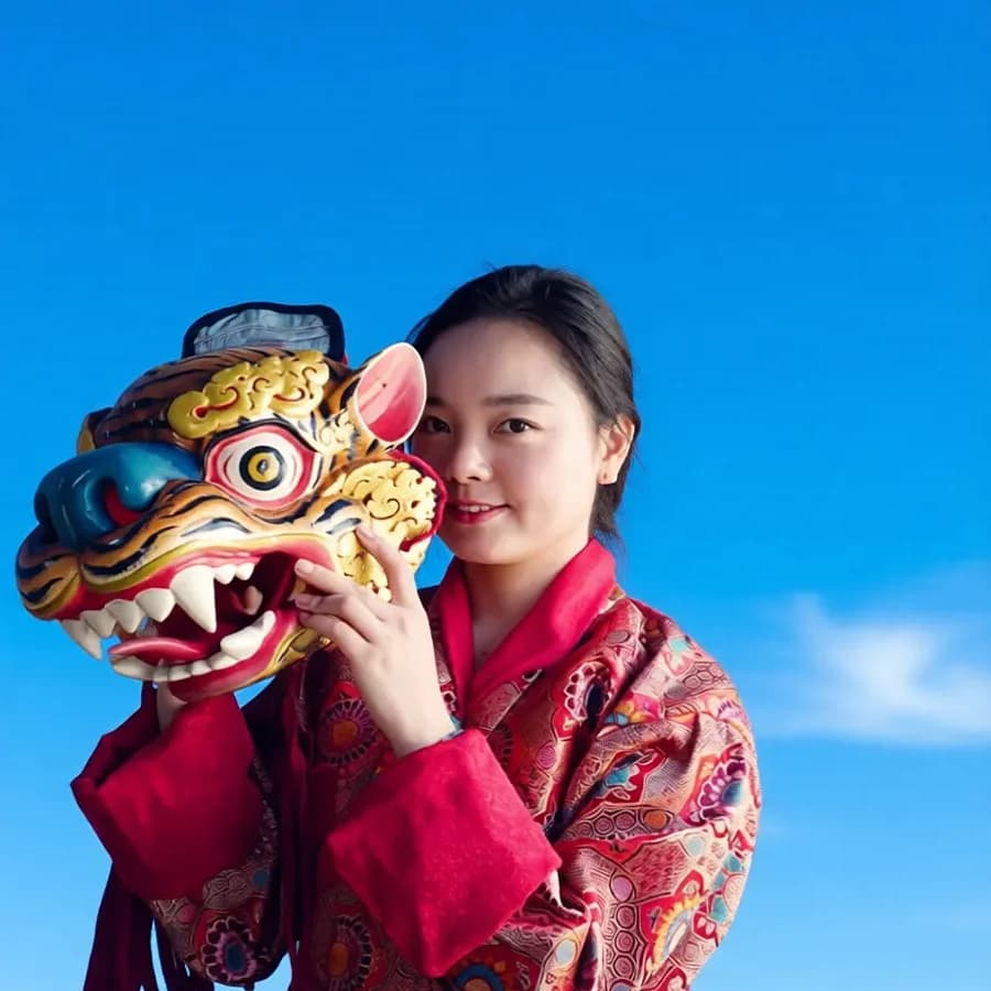 A guest in traditional Bhutanese dress holding a colorful festival mask