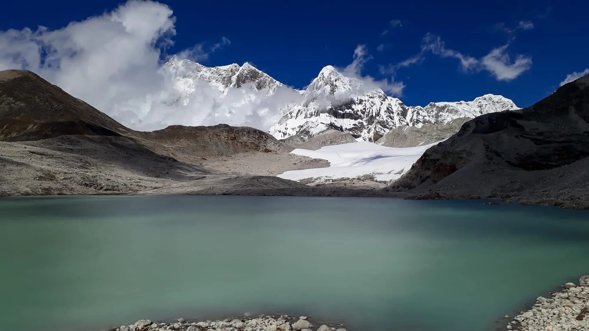 Alpine lake reflecting snow peaks on the Nub Tshonapata trek
